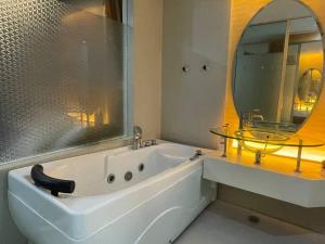 a bathroom with a tub and a sink and a mirror at Private Jacuzzi Luxury Suite at KL City 178 in Kuala Lumpur