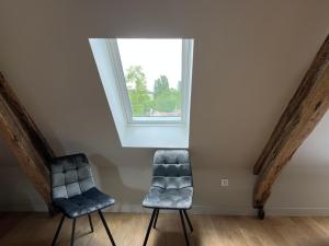 2 sillas en una habitación con ventana en Appartements Domaine Gueguen Chablis en Chablis