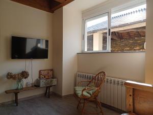 een woonkamer met een tv en een stoel en een raam bij Casa Perdigueira in Castromayor