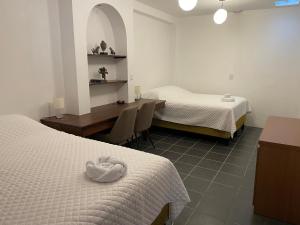 1 Schlafzimmer mit 2 Betten, einem Schreibtisch und einem Tisch in der Unterkunft Hotel Hasta La Vista in Antigua Guatemala