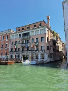 a river with a building and a boat in the water at Sina Palazzo Sant'Angelo in Venice