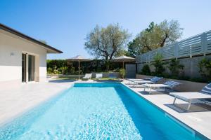 a swimming pool with chairs and umbrellas next to a house at L'Agrumeto in Manerba del Garda