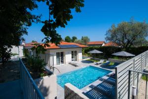 una piscina con sillas y sombrillas junto a una casa en L'Agrumeto, en Manerba del Garda