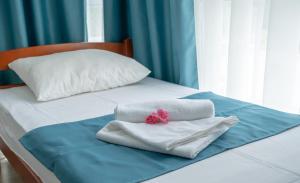 uma cama com toalhas brancas e um laço rosa em Holiday Park Verse em Ulcinj