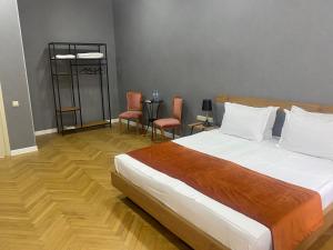 a bedroom with a large bed with chairs and a table at Hotel 1887 in Kutaisi