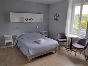 een slaapkamer met een bed en 2 stoelen en een tafel bij Hôtel-Relais De Trefeuntec in Plonévez-Porzay