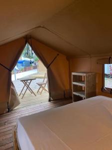 a tent with a bed and a deck with a table at KT-0094 Magnífica Tienda Tipi - Camping Miramar Playa in Torredembarra