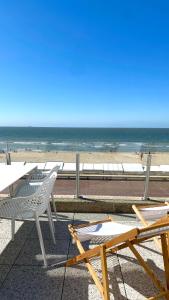 a beach with tables and chairs and the ocean at DeHaanStudio in De Haan