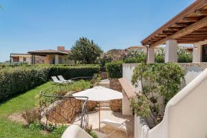 a patio with an umbrella and a table and chairs at Seafront Villa - 5min to BRANDINCHI I Exclusive Garden I Private Beach I BBQ I Wi-Fi in San Teodoro