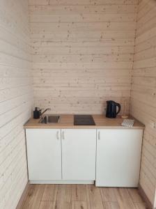 a kitchen with white cabinets and a sink in a room at Nameliai "ŠEŠETAS" in Šventoji