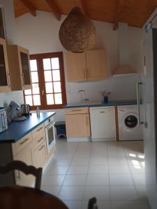 a kitchen with wooden cabinets and a white tile floor at Oléron côte ouest, 3 étoiles in La Cotinière