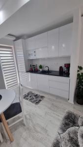 a kitchen with white cabinets and a sink and a table at Apartament Alina Sunrise in Saturn