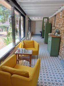 uma sala de espera com cadeiras amarelas e uma mesa em Gîte d'Espinières em Orniac