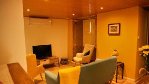 a living room with yellow walls and a tv and chairs at Casarupa do Viriato in Torre de Moncorvo