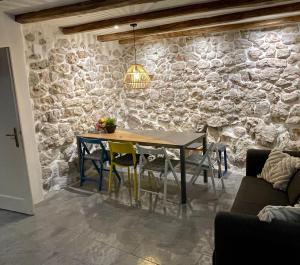 a dining room with a table and a stone wall at Bell Tower House in Novi Vinodolski