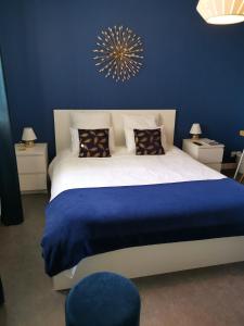 a white bed with a blue and white bedspread at Lamarck Guest in Bourges