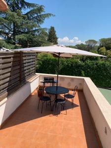 eine Terrasse mit einem Tisch, Stühlen und einem Sonnenschirm in der Unterkunft Just Relax in Le Casette