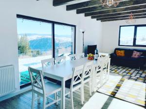 a dining room with a white table and chairs at Black Wood Cabin in Mărişel