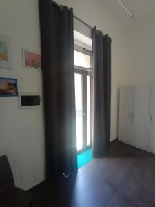 Habitación vacía con ventana grande con cortinas negras en Casa Oliver, en Palazzolo Acreide