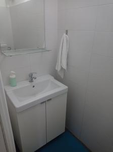 Baño blanco con lavabo y espejo en Casa Oliver, en Palazzolo Acreide