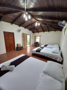 a bedroom with three beds and a wooden ceiling at Hotel Catarata Río Celeste in Bijagua