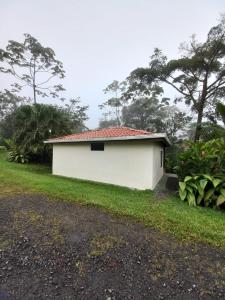 a small white building with a red roof at Hotel Catarata Río Celeste in Bijagua