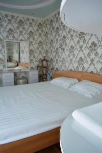 a bedroom with a bed with white sheets and wallpaper at Hiva in Yakkasaray