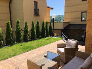 a patio with chairs and a table and trees at Apartman 3M Lux in Vrnjačka Banja