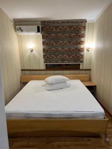 Cette petite chambre comprend un lit avec un drap blanc. dans l'établissement Hiva, à Yakkasaray