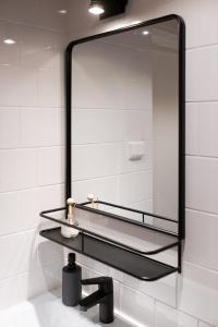 a mirror on a wall above a bathroom sink at Upea studioasunto historiallisella Hangon Asemalla in Hanko