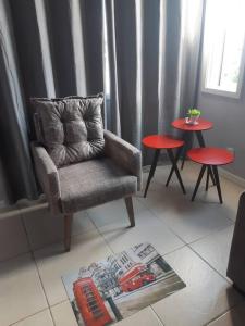 a living room with a chair and two tables at Apartamento London - Centro Nova Petrópolis in Nova Petrópolis