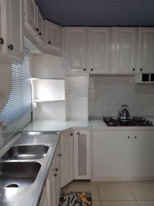 a white kitchen with white cabinets and a sink at Apartamento London - Centro Nova Petrópolis in Nova Petrópolis