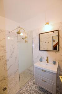 een badkamer met een wastafel en een douche met een spiegel bij Le Logis du Beffroi in Sancerre