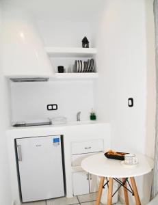 a white kitchen with a small table and a white refrigerator at Galini Studios in Mikri Vigla