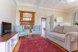 a living room with a couch and two blue chairs at Middelberg Manor in Pretoria