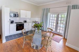 una cocina con mesa y sillas y una cocina con armarios blancos. en Middelberg Manor en Pretoria