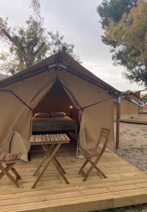 Zelt mit einem Bett und zwei Stühlen auf einer Terrasse in der Unterkunft KT-0094 Magnífica Tienda Tipi - Camping Miramar Playa in Torredembarra