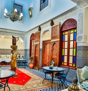 una sala de estar con mesas y sillas y una habitación con subapuntura en Riad Dilar Fes & Spa, en Fez