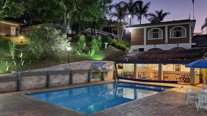 uma piscina em frente a uma casa à noite em Chalés Vila da Serra em Serra Negra