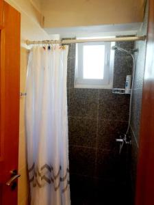 a bathroom with a shower curtain and a window at Stefanel View-Frederika in Himare