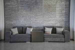 two couches sitting in front of a stone wall at Royal Bay Suites in Kefalos