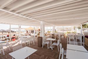a restaurant with white tables and chairs and windows at Hotel Villa del Mare in Senigallia