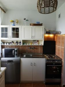 cocina con armarios blancos, fregadero y fogones en A summer house Zarabie Domek letniskowy Zarabie en Myślenice