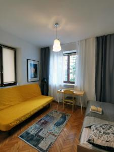 a living room with a yellow couch and a table at Ohotelik Pensjonat w Poniatowej in Poniatowa