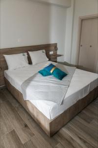 a large bed with white sheets and blue pillows at elenamou seaview rooms in Ammouliani