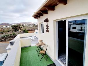a balcony with green flooring and chairs on a house at Apartamento en Mala con vista al mar in Mala