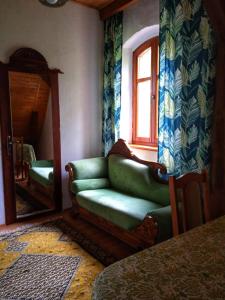 a living room with a green couch and a mirror at Leśniczówka Zawilec in Budry