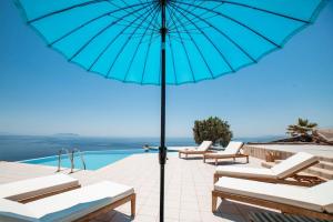 a blue umbrella sitting on a patio next to a swimming pool at Kea Ciel Villa in Ioulis +35 photos