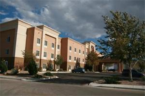 a row of apartment buildings on a street with a tree at Hampton Inn & Suites Hobbs in Hobbs