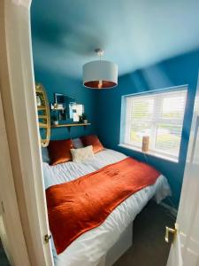 a bedroom with blue walls and a bed with an orange blanket at Coastal 2 bedroom maisonette with parking in Eastbourne